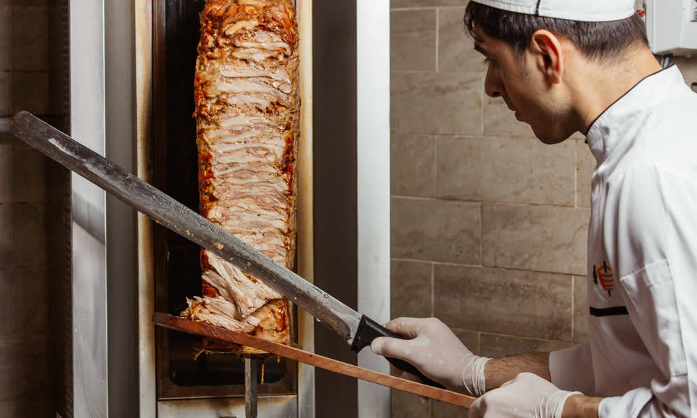 Döner ustası ocak başında yaprak döner keserken